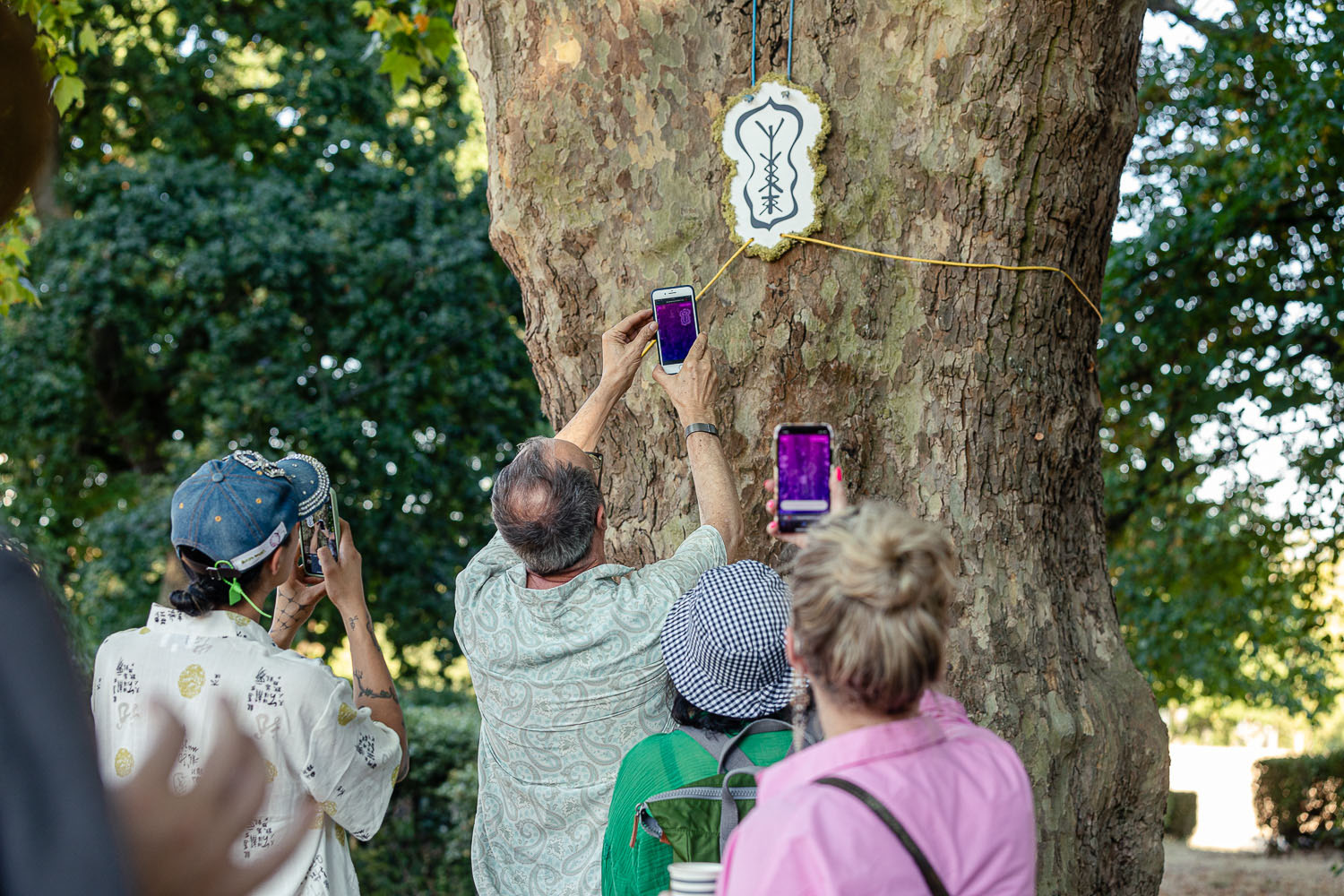 alt: Park users scanning a shape hanging from the tree in order to trigger the AR interaction with the sprites