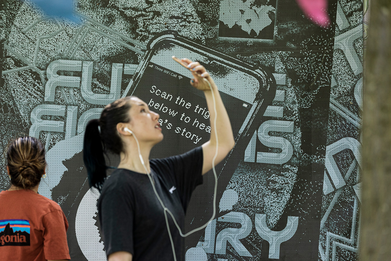 woman holding up her phone, standing in front a future fictions sign