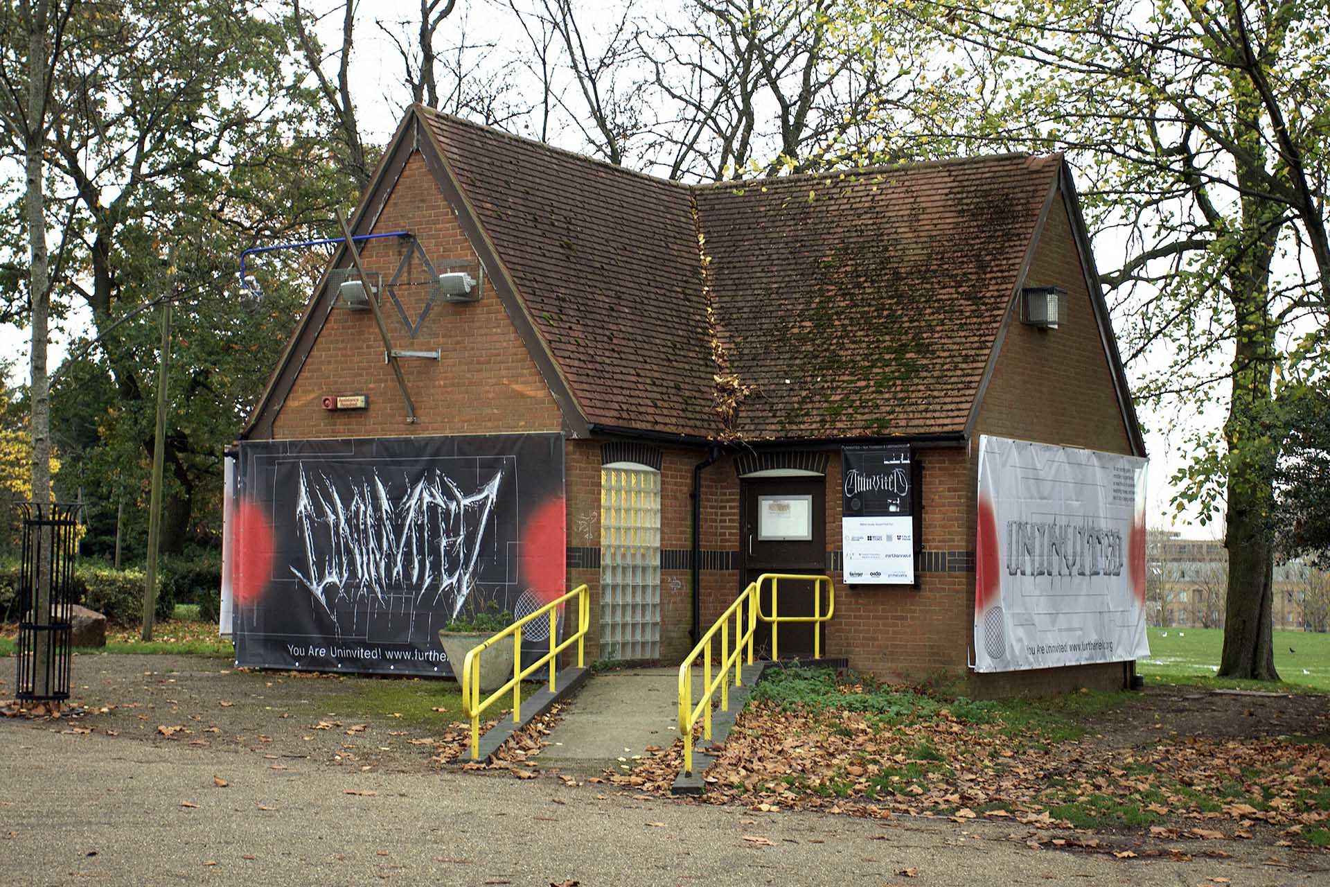 Image shows Furtherfield Gallery in Finsbury Park, covered by large hoardings displaying the uninvited branding and logotypes